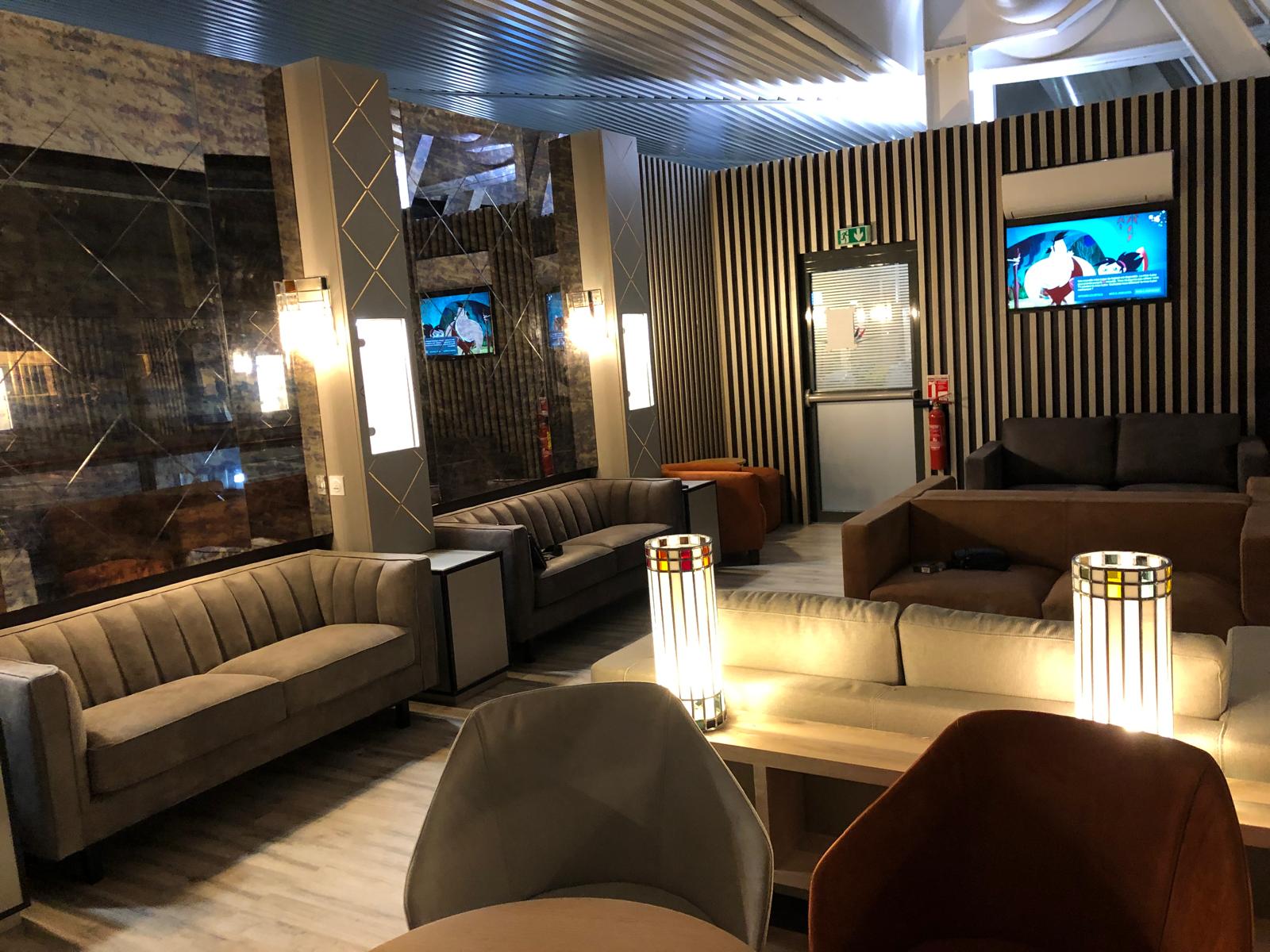 Bar-lounge aménagé — banquettes, habillage bois à claustra et éclairage d'ambiance