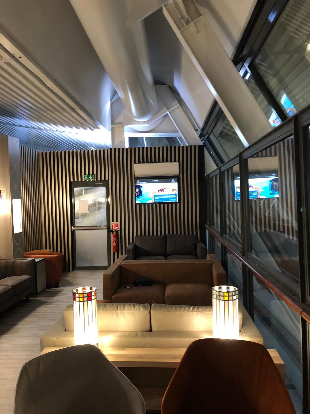 Espace détente du lounge — claustra bois, écrans encastrés et climatisation intégrée