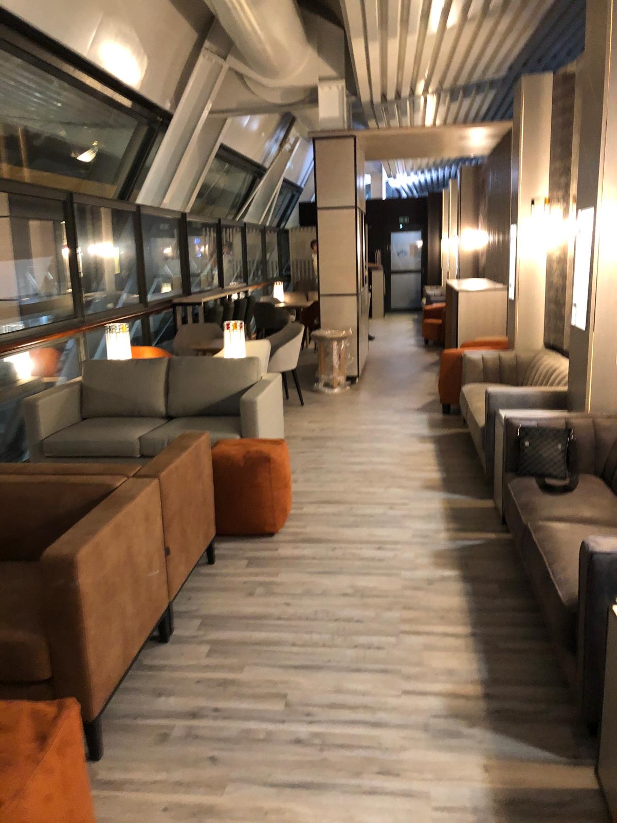 Enfilade du lounge le long de la verrière inclinée — banquettes et circulation dégagée
