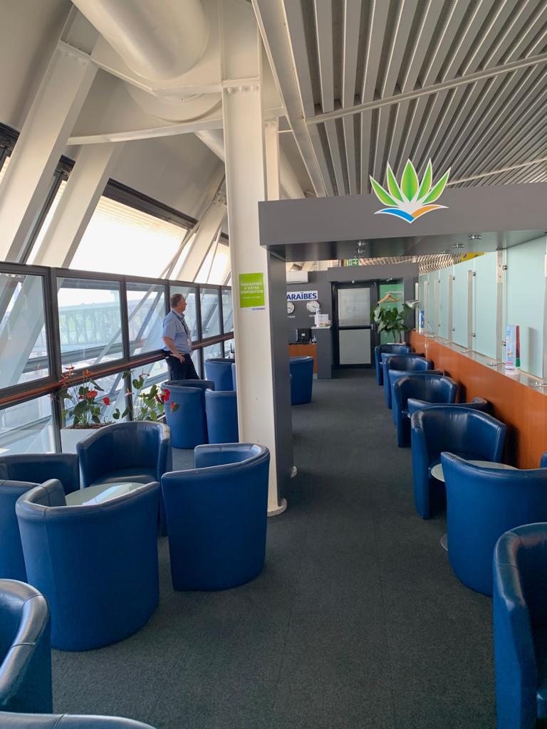 Salon VIP aménagé — fauteuils bas, banque d'accueil et vue panoramique sur la verrière